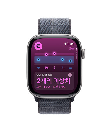 활력 징후 앱, 건강 점수 차트, 야간 활력 징후 이상치 알림이 표시되고 오른쪽 옆면 외관에 Digital Crown이 보이는 스페이스 그레이 색상 알루미늄 케이스의 Apple Watch Series 11, 그리고 다크 그레이 색상 스포츠 루프