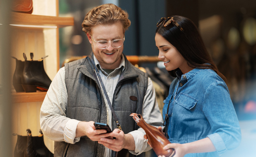 Un vendedor usa el iPhone en la tienda para ayudar a una clienta.