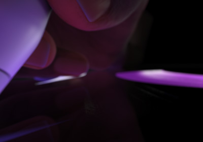 Lietotājs tur Apple Pencil Pro kā rakstāmrīku. Pie displeja piespiests rakstāmgals zīmē biezas, spilgti violetas līnijas.